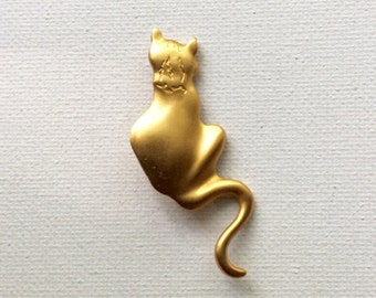 以下が含まれることがあります： 尻尾を体に巻き付けた座っている猫の形をした金色の金属製のブローチです。