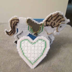 Puede incluir: Artesanía de hilo blanco de un caballo de carrusel con una crin y cola marrones, y un corazón verde.