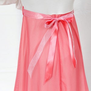 May include: A coral pink tulle skirt with a satin ribbon tied in a bow at the back.