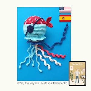 Puede incluir: Un juguete de medusa de ganchillo con temática pirata. La medusa tiene una cabeza con estampado rojo y blanco, un cuerpo azul y un parche en el ojo negro. Sus tentáculos son azules, blancos y rojos sobre un fondo azul.