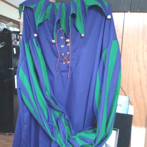 May include: A purple and green jester costume shirt with a lace-up front and bells on the collar and sleeves.