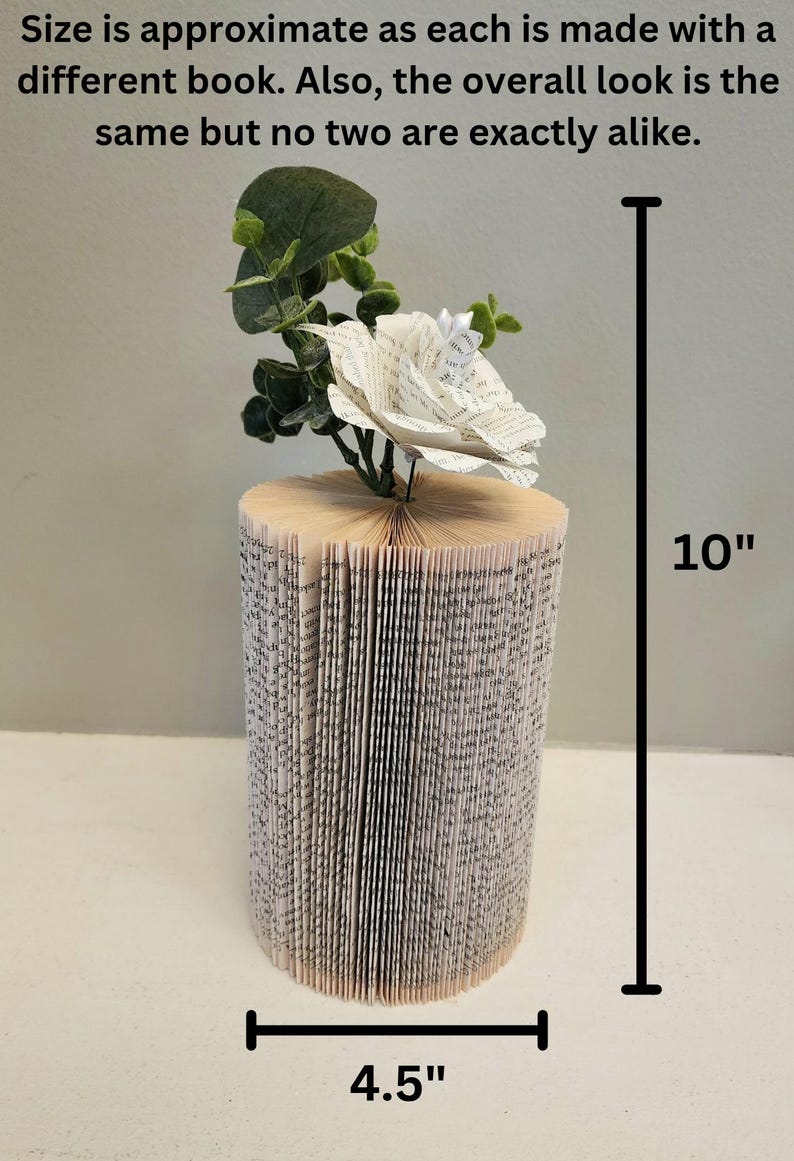 Puede incluir: Un arreglo de flores de papel blanco en un jarr&oacute;n de libro. El jarr&oacute;n est&aacute; hecho de un libro que se ha doblado en forma de cilindro. El jarr&oacute;n mide 10 pulgadas de alto y 4,5 pulgadas de ancho.