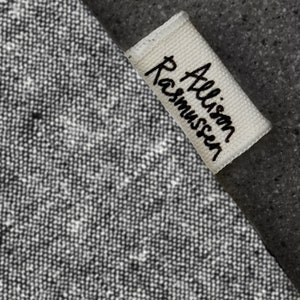 Pu&ograve; includere: Un'etichetta in tessuto bianco con testo nero che recita "Allison Rasmussen".