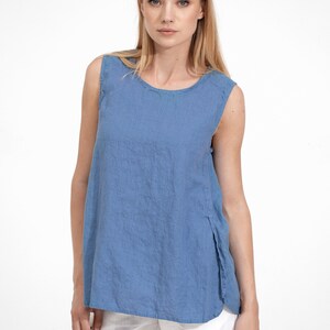 May include: A sleeveless, light blue linen top with a round neckline. The top has a relaxed fit and a slightly longer length in the back.