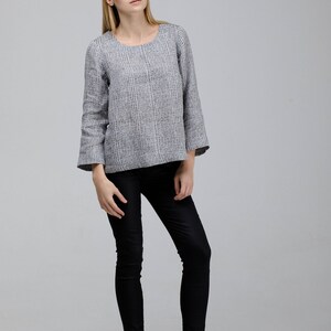 May include: A woman wearing a gray and white striped long-sleeved shirt with black pants and black ankle boots.