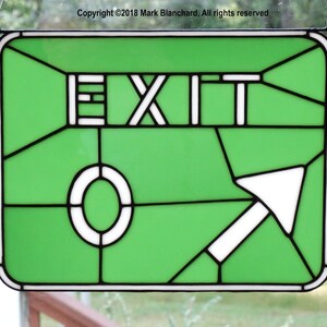 May include: A green stained glass sign with a white arrow pointing to the right and the word "EXIT" in white letters.