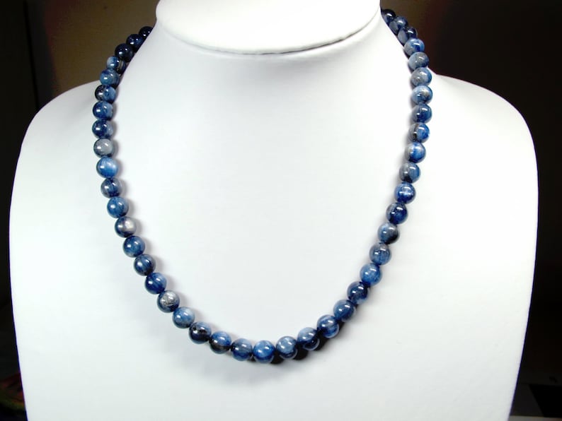 May include: A blue gemstone necklace with round beads. The necklace is made of blue kyanite beads.