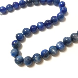 May include: A strand of blue gemstone beads. The beads are round and have a smooth, polished finish. The beads are strung on a clear thread.