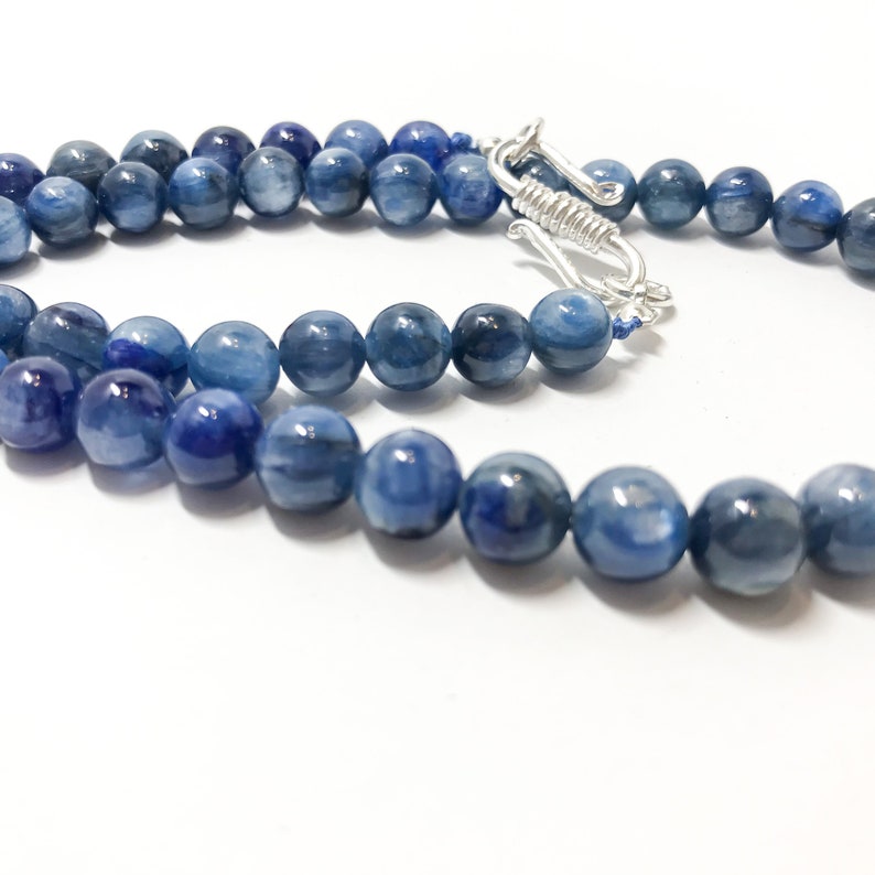 May include: A blue gemstone necklace with a silver clasp. The necklace is made of round beads and is approximately 18 inches long.