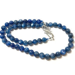 May include: A blue gemstone necklace with a silver clasp. The necklace is made of round beads and is approximately 18 inches long.