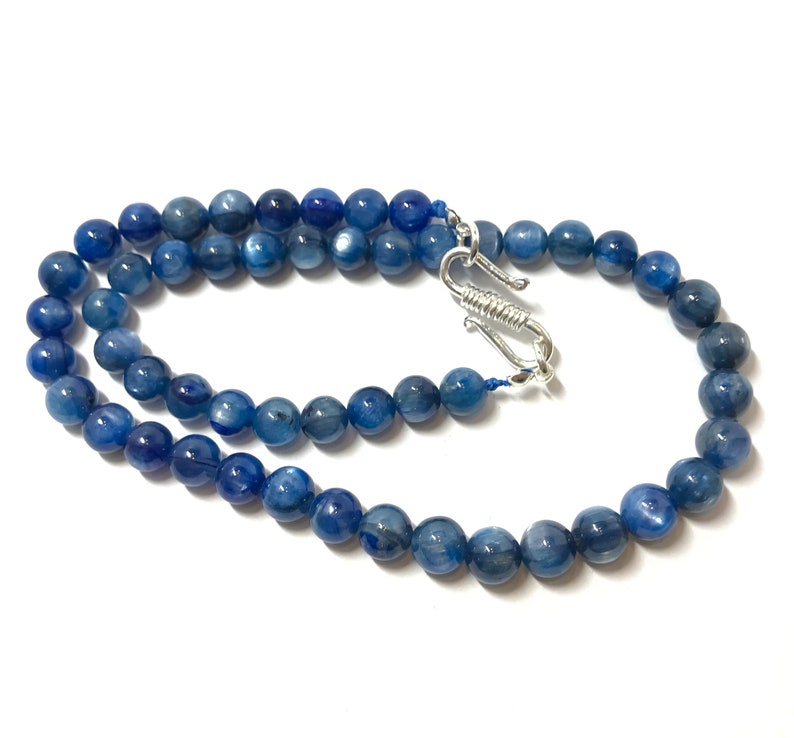May include: A blue gemstone necklace with a silver clasp. The necklace is made of round beads and is approximately 18 inches long.