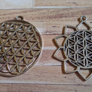 May include: Two silver metal pendants featuring a flower of life design. One pendant is a circle and the other is a flower shape.