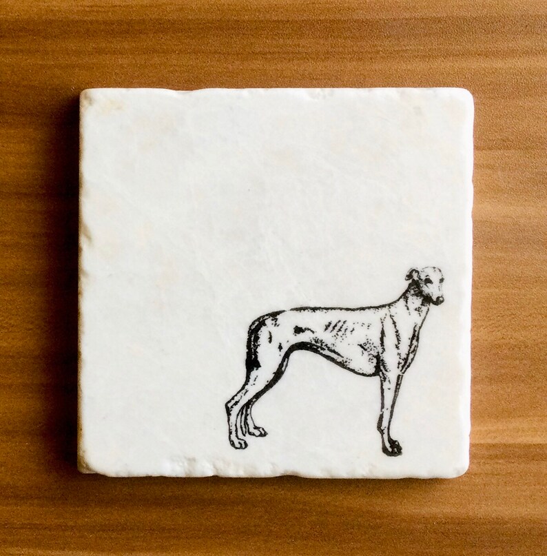 Op de afbeelding: Vierkante witte marmeren onderzetter met een zwarte illustratie van een windhond. De hond is in profiel afgebeeld. De onderzetter heeft een licht getextureerd oppervlak.