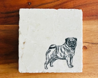 May include: Square, off-white stone coaster with a black and white illustration of a pug dog. The coaster is set on a wooden surface. The pug is facing right, with detailed shading.