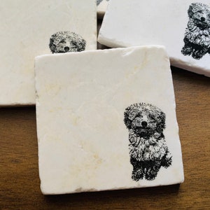 May include: Set of four white marble coasters with a black and white image of a dog on each coaster.