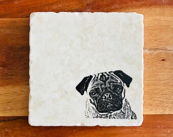 May include: Square, off-white marble coaster featuring a black and white illustration of a pug dog's face. The coaster has a slightly textured surface and is set against a wooden background.