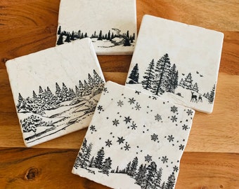 Puede incluir: Conjunto de cuatro posavasos cuadrados con un tema de bosque de invierno. Cada posavasos presenta un diseño diferente, que incluye un bosque nevado, un bosque con un ciervo y un bosque con copos de nieve. Los posavasos están hechos de mármol blanco con diseños de tinta negra.