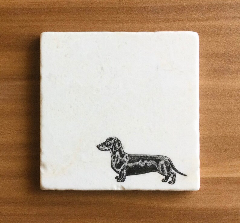 Pu&ograve; includere: Sottobicchiere in marmo bianco con una silhouette nera e bianca di un bassotto.