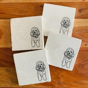 May include: Set of four white square coasters with a black line drawing of a dog on each coaster.