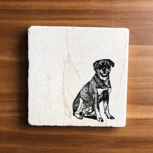 May include: A white marble coaster with a black and white silhouette of a Rottweiler dog sitting.