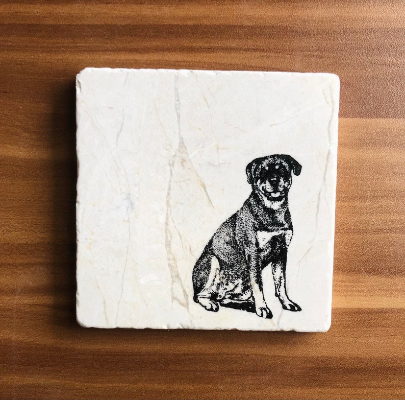 May include: A white marble coaster with a black and white silhouette of a Rottweiler dog sitting.