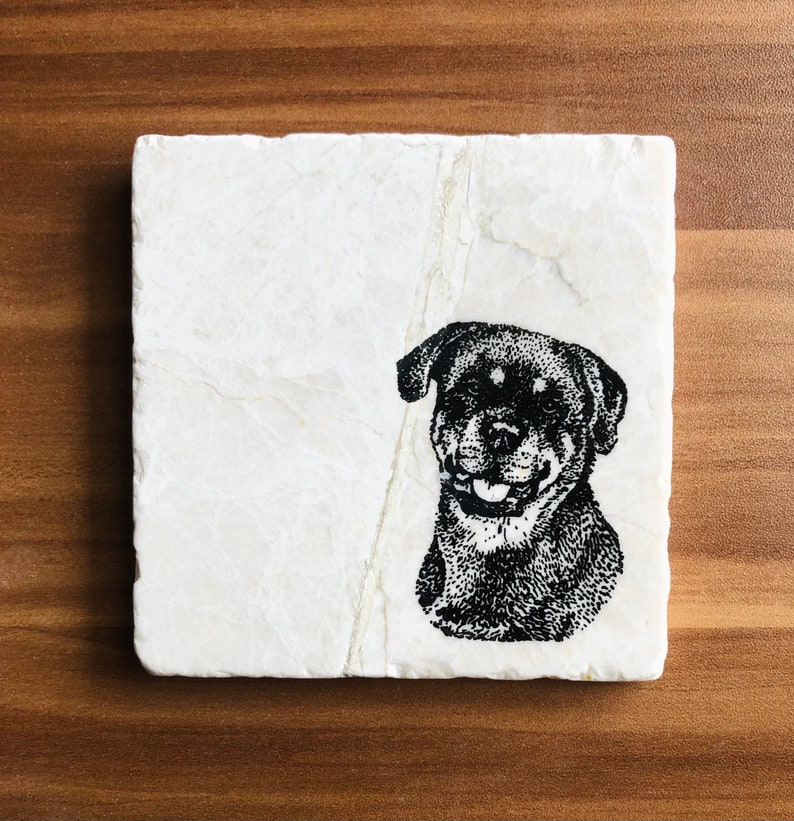 May include: A white marble coaster with a black and white illustration of a Rottweiler dog.