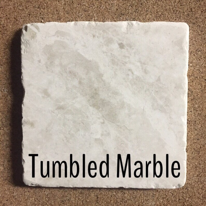 May include: A close-up of a white, tumbled marble tile. The tile has a rough, textured surface. The text "Tumbled Marble" is printed on the tile.