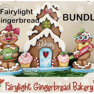 May include: A festive gingerbread bakery scene with a gingerbread house, two gingerbread people, and two cupcakes. The gingerbread house has white icing and a heart-shaped door. The text "Fairylight Gingerbread Bakery" is displayed.