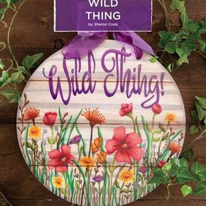 May include: Round wooden sign with the words "Wild Thing!" in purple script. The sign features a floral design with red, yellow, and purple flowers, green grass, and the text "Wild Thing by Sharon Cook".