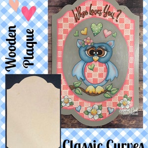 May include: Wooden plaque with a gray background and a pink and white checkered pattern. The plaque features a blue owl with big brown eyes and a pink heart on its chest. The text "Who loves you?" is written in brown at the top of the plaque.