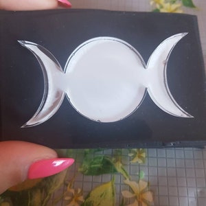 Könnte beinhalten: Eine schwarze Plastikform mit einem dreidimensionalen, weißen Dreimond-Symbol-Ausschnitt. Die Form wird zur Herstellung von Kunsthandwerk aus Harz verwendet.