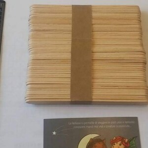 K&ouml;nnte beinhalten: Ein Stapel aus 50 nat&uuml;rlichen Holz-Bastelst&auml;bchen, zusammengebunden mit braunem Klebeband. Die St&auml;bchen sind etwa 11,5 cm lang und 1,5 cm breit.