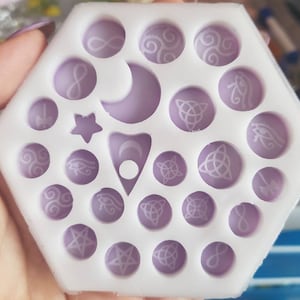 May include: White silicone mould with 20 individual cavities, each containing a different design. The designs include infinity symbols, crescent moons, stars, Celtic knots, and eyes.