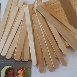 K&ouml;nnte beinhalten: Ein gro&szlig;er Stapel nat&uuml;rlicher Holz-Bastelst&auml;bchen, etwa 100 St&auml;bchen, mit abgerundeten Enden. Die St&auml;bchen sind f&auml;cherf&ouml;rmig angeordnet, wobei sich einige St&auml;bchen &uuml;berlappen.