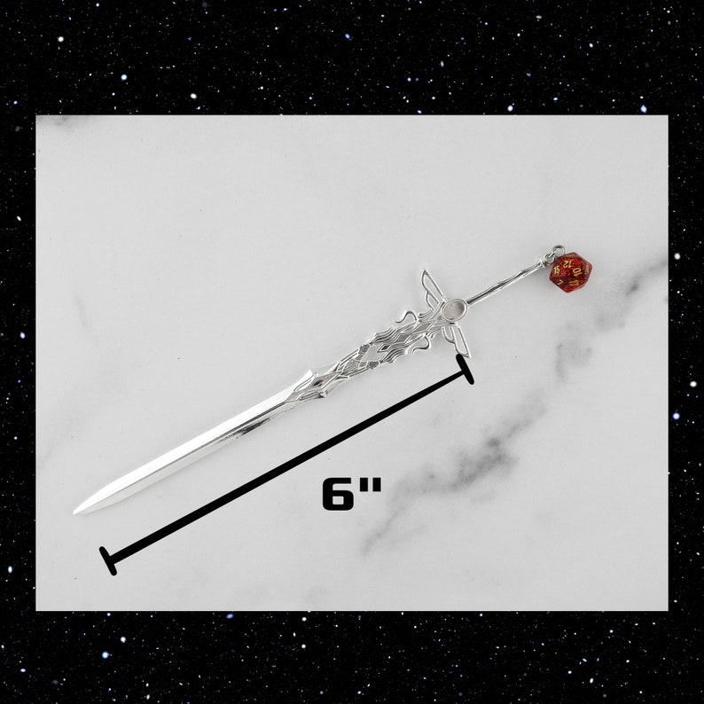 May include: A silver sword hair stick with a red and gold dice charm. The hair stick is 6 inches long.