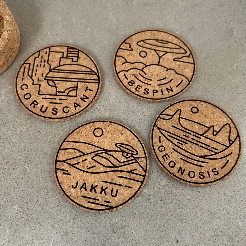May include: Four round cork coasters with black outlines of different Star Wars locations. The coasters feature the names "Coruscant", "Bespin", "Geonosis", and "Jakku".