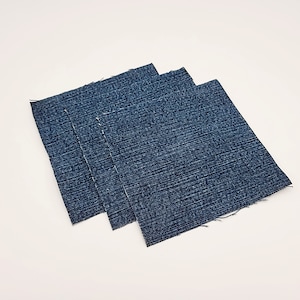 May include: Three squares of blue denim fabric stacked on top of each other.