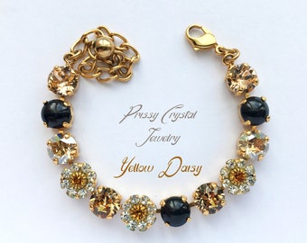 May include: Gold-toned bracelet featuring alternating black and amber-colored crystals, with daisy-shaped accents. The bracelet is labeled "Prissy Crystal Jewelry" and "Yellow Daisy". The clasp and chain are also gold-toned.