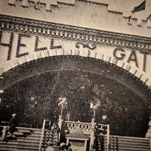 May include: Vintage black and white photograph of the Hell Gate entrance. The arched entrance features the words "HELL GATE" in illuminated letters. The image shows a glimpse of the structure's architecture and the surrounding area.