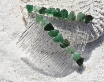 May include: A clear plastic hair comb with green gemstone accents. The comb is decorated with a row of green stones along the top.