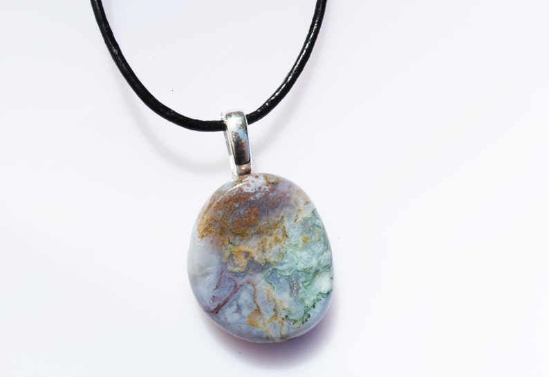 May include: A natural stone pendant necklace. The pendant is an oval shape with a silver bail and a black cord. The stone has a mix of colors, including blue, green, brown, and white.