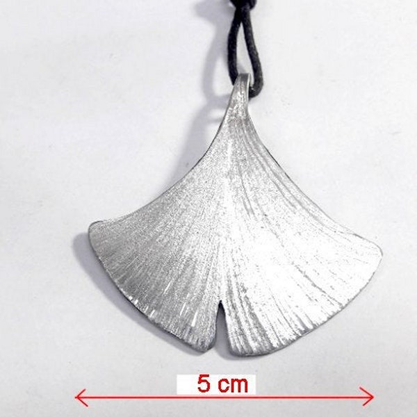 Pendentif en aluminium représentant une feuille de Ginkgo Biloba avec un texte personnalisé.