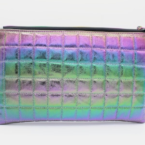 Puede incluir: Un embrague acolchado iridiscente con cierre de cremallera. El embrague está hecho de una tela metálica con una textura sutil. La tela es un degradado de morado, azul, verde y dorado.