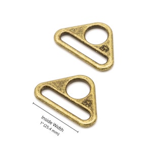 May include: Two antique gold triangle-shaped metal slider buckles, each with a 1 inch (2.54 cm) inside width. The buckles have a slightly textured surface and are marked with the letter "B" inside a circle.