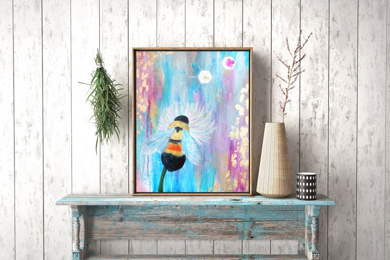 May include: A painting of a bumblebee on a flower with a blue, pink, and gold background. The bee is yellow and black with white wings. The flower is white with a blue center. The background is abstract with a honeycomb pattern.