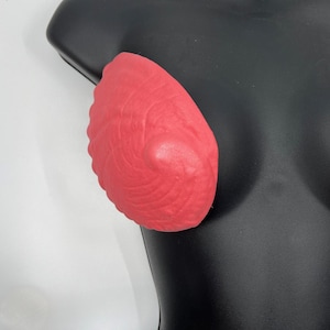 May include: A pair of red silicone breast enhancers with a textured surface.