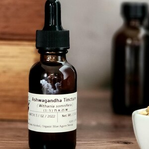 May include: A brown glass bottle with a black dropper top and a white label that reads "Ashwagandha Tincture (Withania somnifera) (1:5) 75 A: 25 W BATCH: 3/02/2022 Net Wt. (1 oz) Grain Alcohol, Organic Blue Agave Nectar".