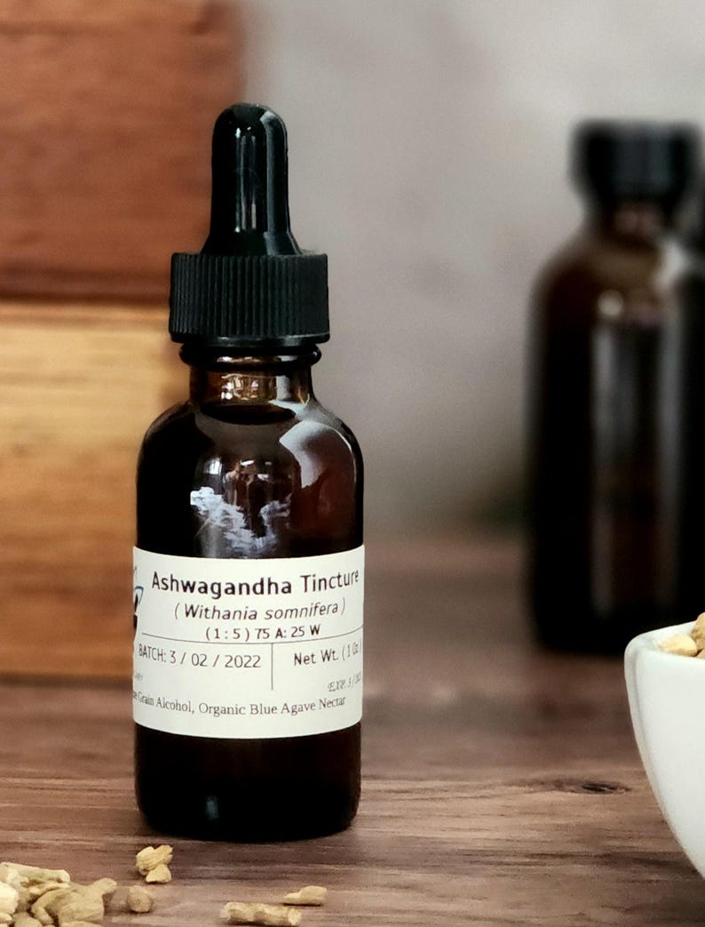 May include: A brown glass bottle with a black dropper top and a white label that reads "Ashwagandha Tincture (Withania somnifera) (1:5) 75 A: 25 W BATCH: 3/02/2022 Net Wt. (1 oz) Grain Alcohol, Organic Blue Agave Nectar".