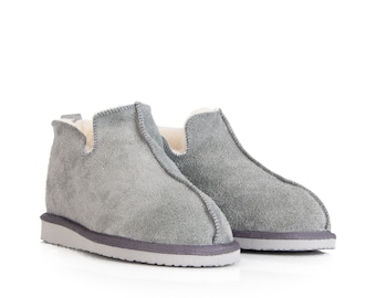 May include: A pair of gray suede slippers with a soft, fuzzy lining. The slippers have a simple, slip-on design and a comfortable, cushioned sole.