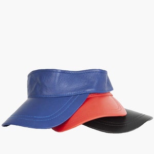 May include: Three leather visors in blue, red and black. The visors are stacked on top of each other.